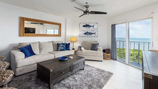 A living room with a sofa, coffee table, and a view of the sea through large windows. - Captains Quarters Ocean Pointe 4405 (Tavernier)