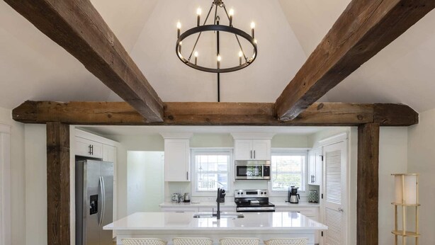 A spacious kitchen with a large island, wooden beams, white cabinetry, and a chandelier. - Cape Henry Full Suite Inn at Old Beach (Virginia Beach)