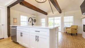 A spacious kitchen with white cabinetry, a large island, and a wooden floor. - Cape Henry Full Suite Inn at Old Beach (Virginia Beach)