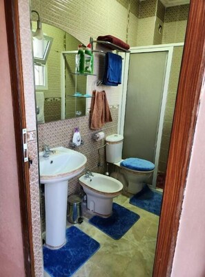Ein Badezimmer mit zwei Waschbecken, einer Toilette und einer Dusche. Handtücher und Pflegeprodukte sind vorhanden.
