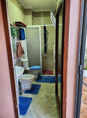 Ein kleines Badezimmer mit zwei Toiletten, einem Waschbecken und einer Duschkabine.