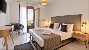 Una habitación de hotel moderna con una cama grande, un escritorio, una silla y un balcón con cortinas.