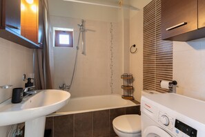 Une salle de bain moderne équipée d’une baignoire, de toilettes et d’un lave-linge.