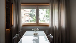 Un coin repas comprenant une table, des chaises et une fenêtre avec des rideaux.