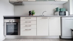 Une cuisine moderne dotée d’appareils électroménagers en acier inoxydable, de meubles blancs et d’un four encastré.