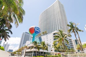 A tall hotel with a distinctive blue and red sign reading 'Hallsand Beach' and a modern architectural design.