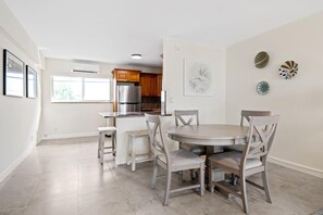 A modern kitchen with a built-in refrigerator, wooden cabinets, and a dining area with a round table and four chairs.