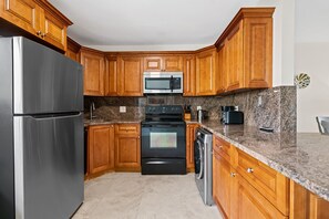 A kitchen with wooden cabinets, stainless steel appliances, granite countertops, and a dishwasher.