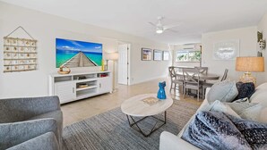 A spacious living area with a large painting, a dining table, and a ceiling fan. - Bermuda Isles Villas - King #30 (Lauderdale-by-the-Sea)