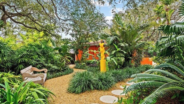 Un sentier de jardin agrémenté de pas japonais, un banc et une végétation luxuriante.