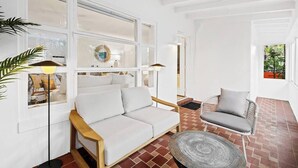 A modern living room with a white sofa, a wicker chair, and a round table.