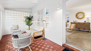 A modern interior with a white brick wall, wicker furniture, a round table, and a decorative mirror.