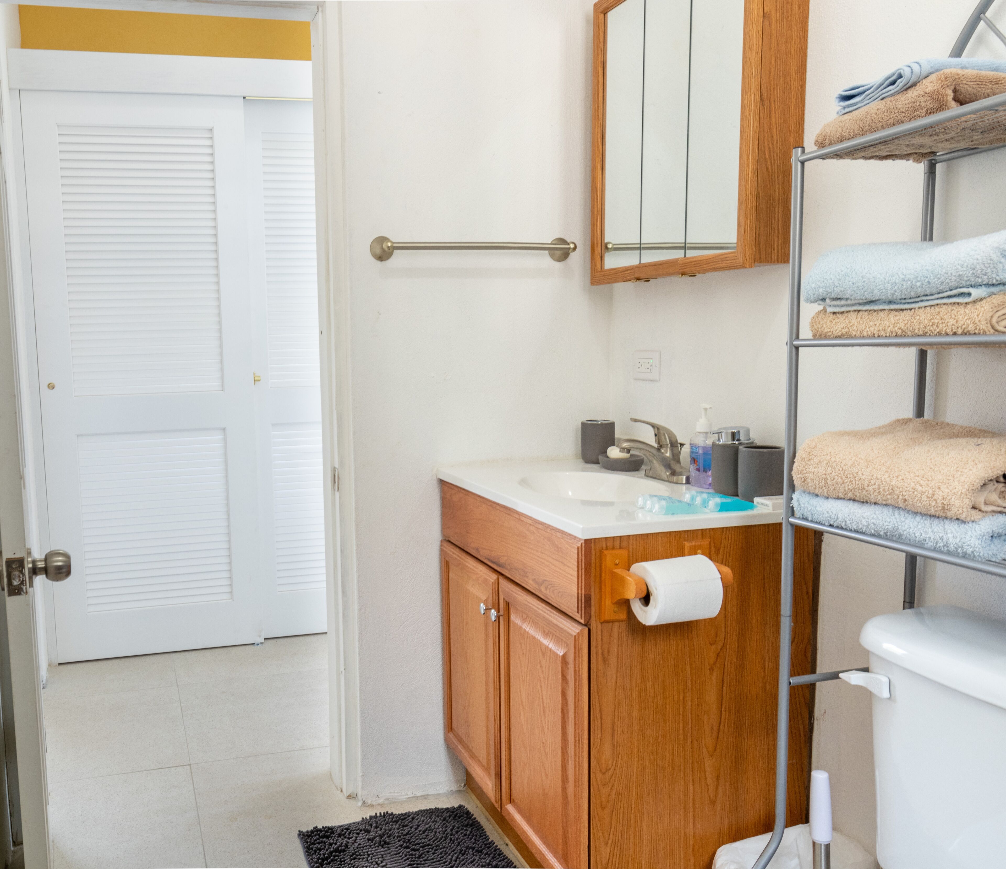 Une salle de bain avec un meuble-lavabo en bois, un lavabo blanc, un miroir et un porte-serviettes.