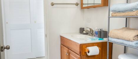 Une salle de bain avec un meuble-lavabo en bois, un lavabo blanc, un miroir et un porte-serviettes.