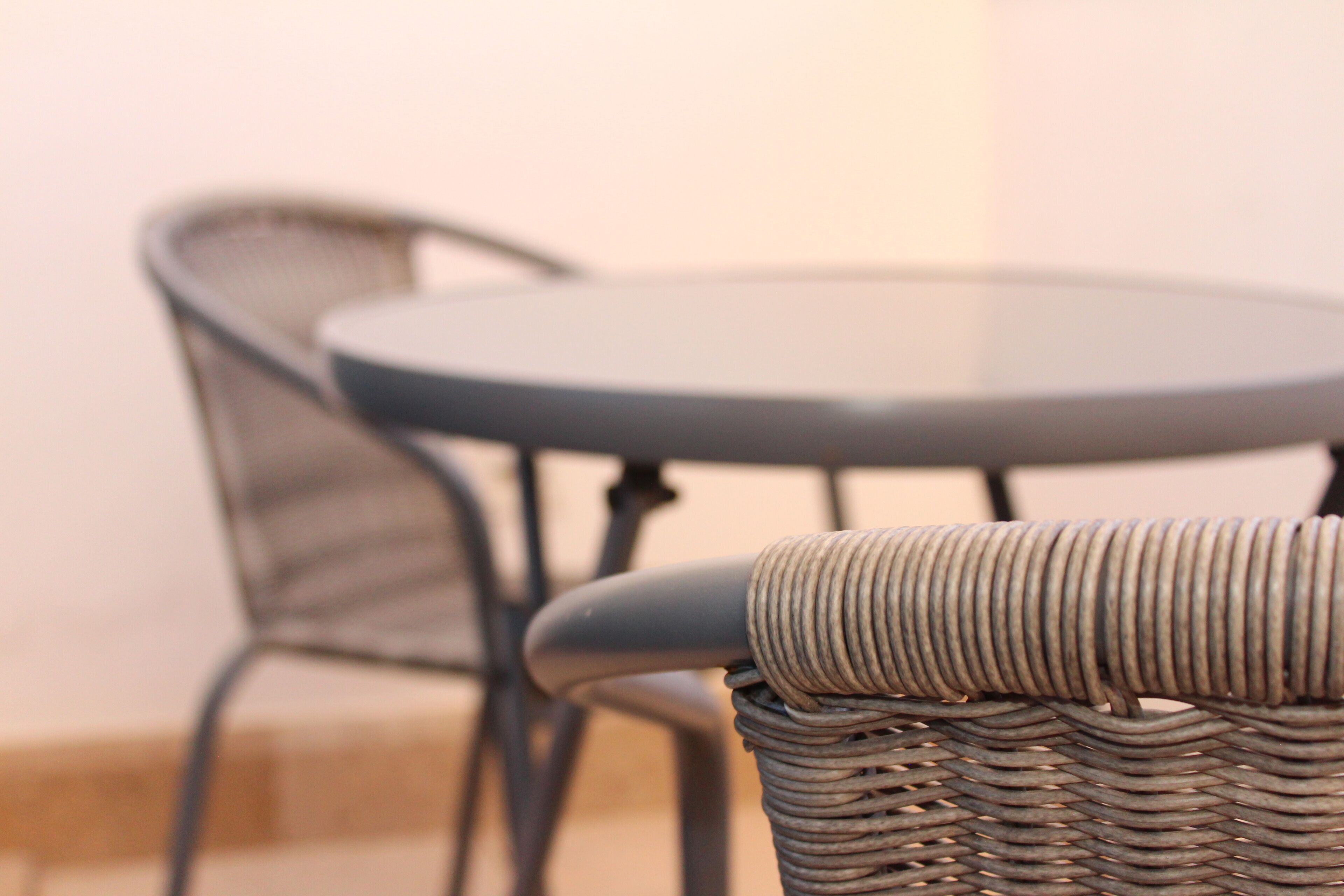 Une chaise en osier avec une structure en métal et une table ronde.