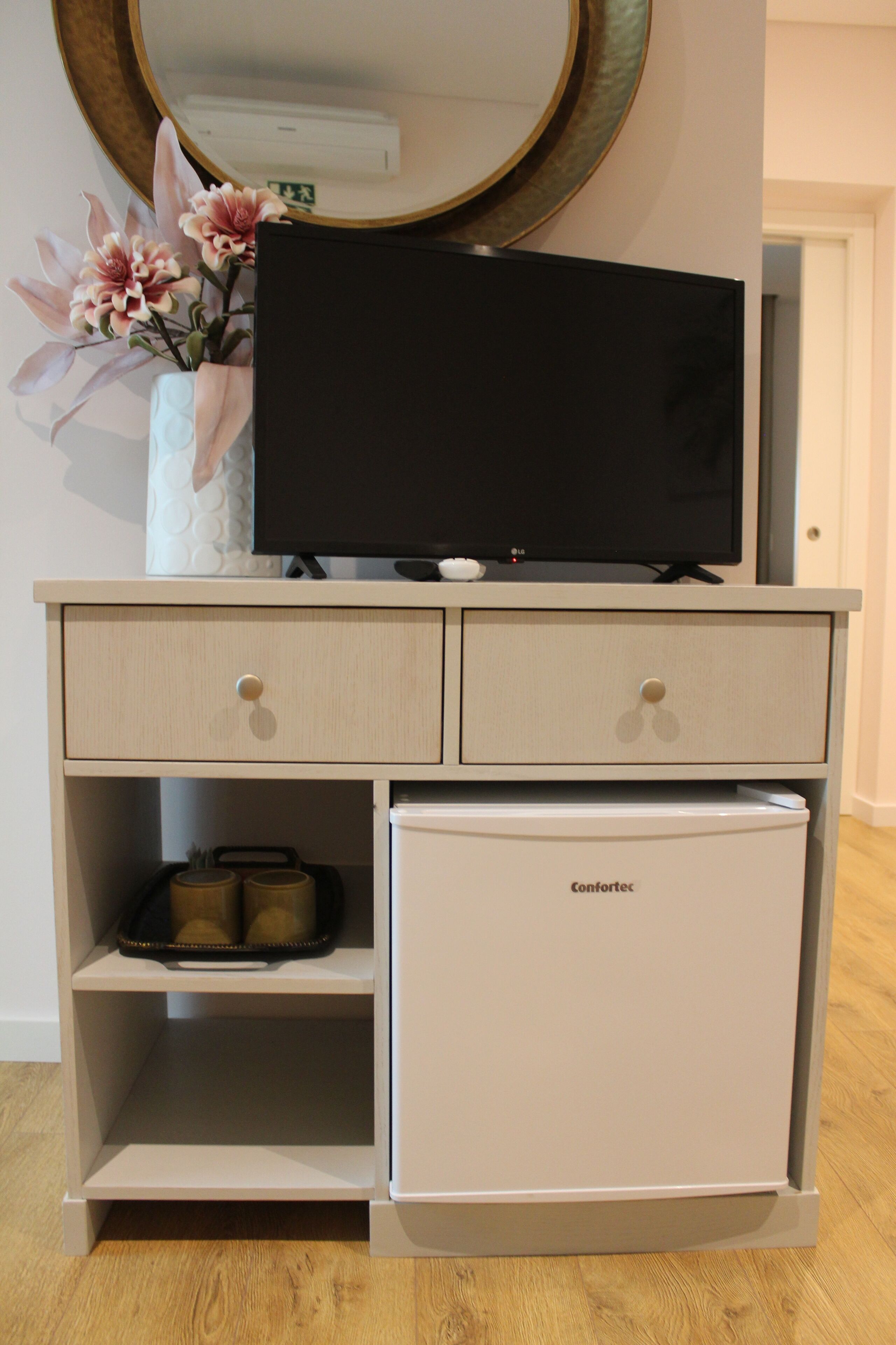 A compact minibar with a refrigerator, a flat-screen TV, and a small shelf with a tray.