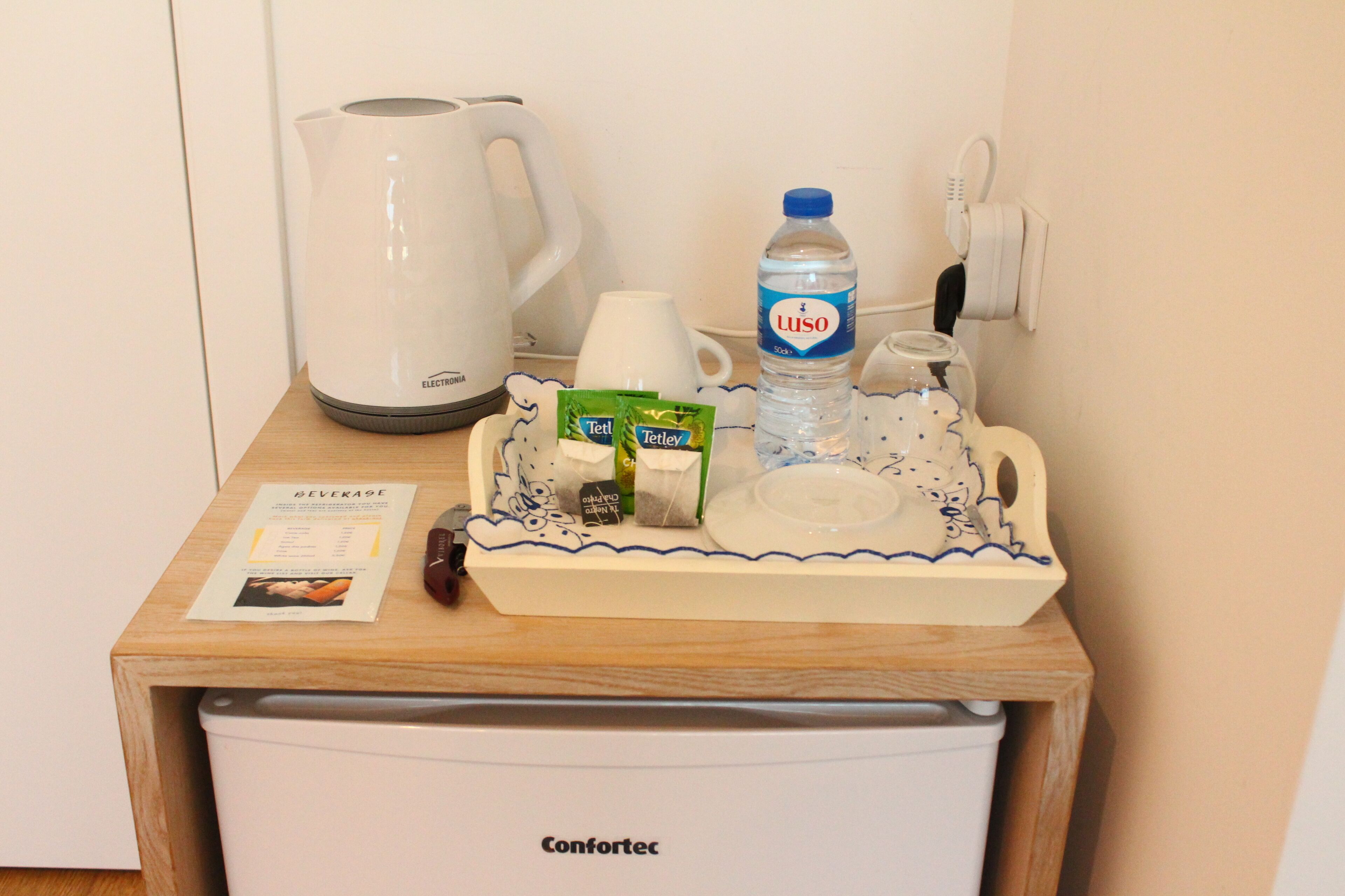 A minibar with a water bottle, tea packets, a coffee maker, and a tray.