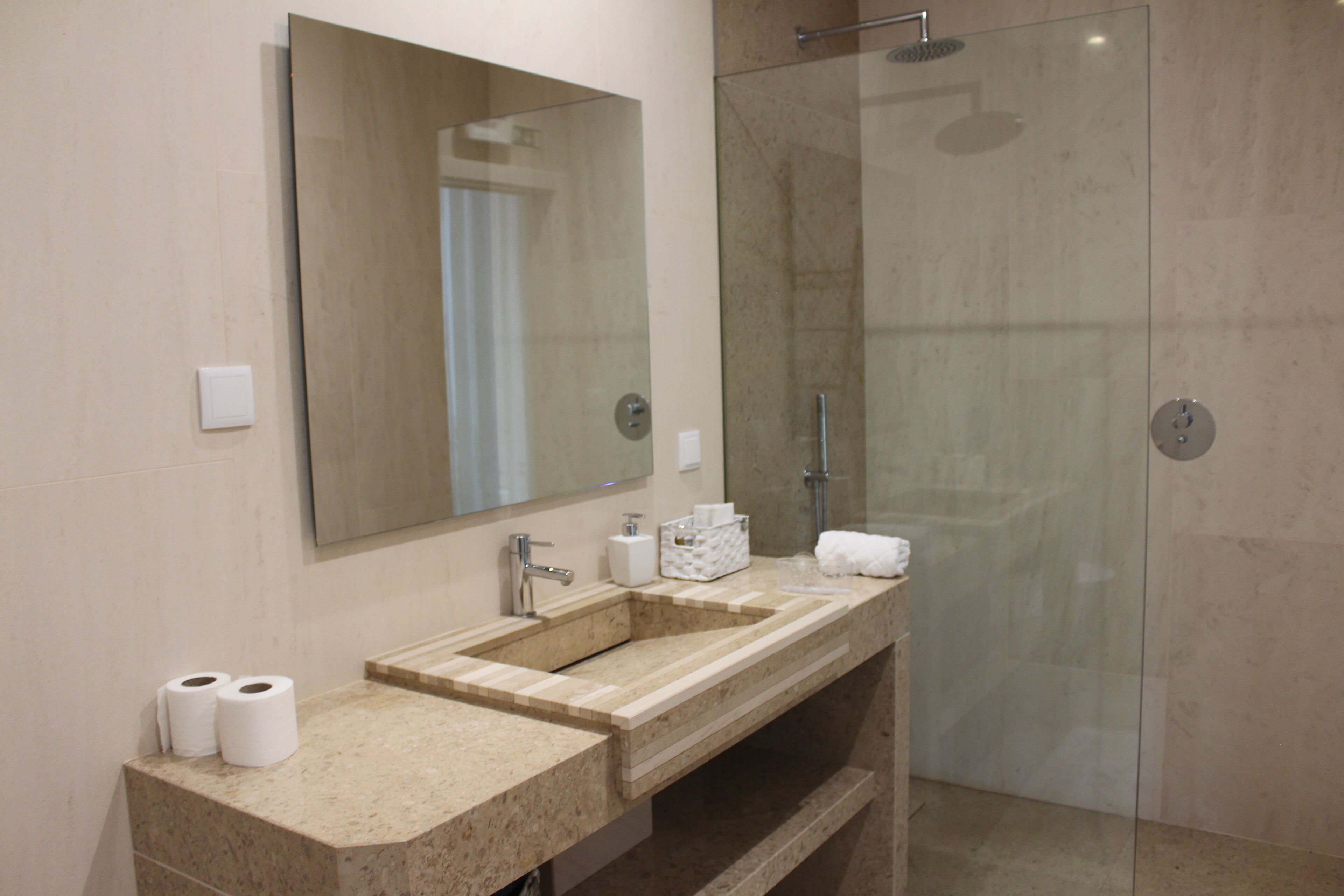 Een badkamer met een grote spiegel, twee wastafels, een douche en een toilet.