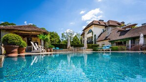 Piscina límpida com espreguiçadeiras e plantas em vasos.