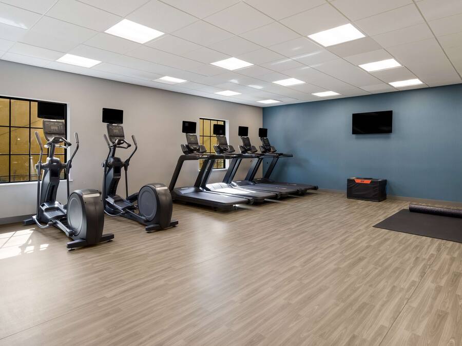 A gym with treadmills, elliptical machines, and a yoga mat area.