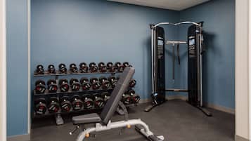 A gym with a bench, dumbbells, and a squat rack.
