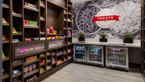 A candy and snack display area with shelves stocked with various brands and a refrigerated section. - Hampton Inn Concord (Concord)