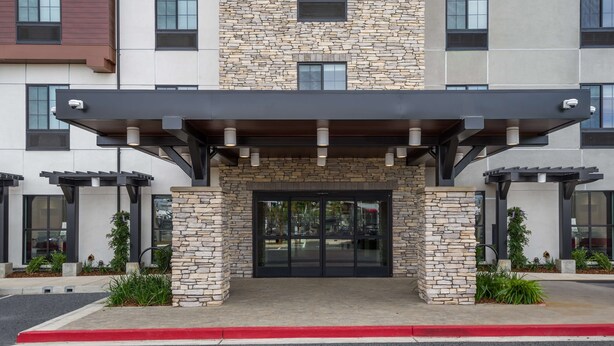 A modern building with a stone facade, a covered entrance, and a red curb. - Hampton Inn Concord (Concord)
