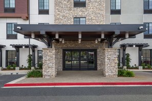 A modern building with a stone facade, a covered entrance, and a red curb. - Hampton Inn Concord (Concord)