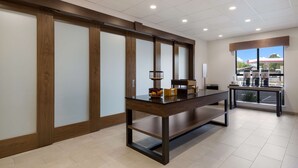 A modern hotel room with a wooden-framed sliding door, a large window with a view of the outside, and a table with a lamp and a box. - Hampton Inn Concord (Concord)