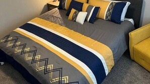 A neatly made bed with a geometric patterned bedspread, a dark headboard, and a single bedside table with a lamp. - Location, Location in cedarburg (Cedarburg)