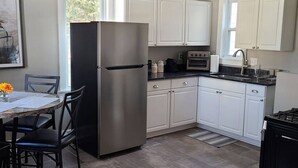 A modern kitchen with white cabinets, a stainless steel refrigerator, a gas stove, and a dining area with a table and chairs. - Location, Location in cedarburg (Cedarburg)