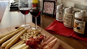 Un comptoir de cuisine avec une planche à découper pour charcuterie, un verre à vin et des condiments.