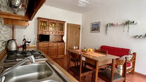 Une cuisine dotée d’éviers en acier inoxydable, de meubles de rangement en bois, d’une table à manger avec des chaises et d’un luminaire suspendu.
