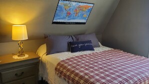 Un dormitori amb un llit, un mapa del món a la paret, una làmpada i una finestra.
