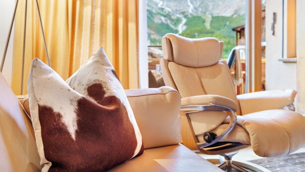 Ein Zimmer mit großem Fenster, Ledersofa und Massagesessel.