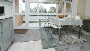 A modern kitchen with a built-in TV, a dining area with a table and chairs, and a large sliding glass door leading to a balcony.