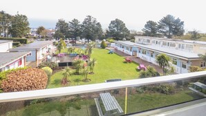 A view of a caravan park with multiple caravans and a grassy area with picnic tables.