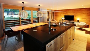Een moderne keuken met een centraal eiland, houten keukenkastjes en hanglampen.
