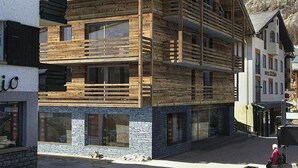 Een meerlaags houten gebouw met balkons, grote ramen en een stenen basis.