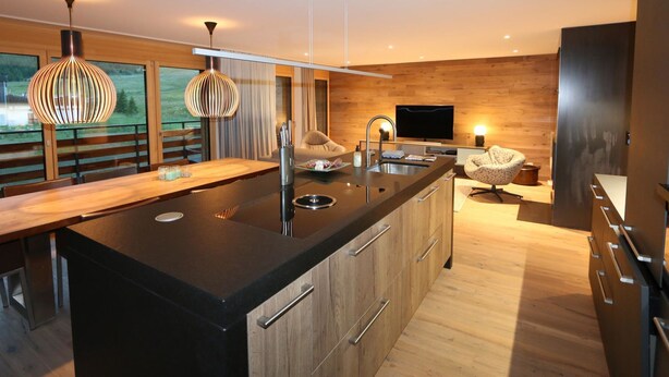 Een moderne keuken met een groot eiland, houten kastjes en hanglampen.