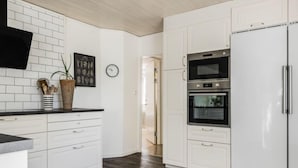 A modern kitchen with white cabinetry, a black countertop, and a stainless steel refrigerator.