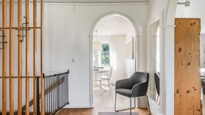 A hallway with a wooden railing, a grey rug, and a black chair.