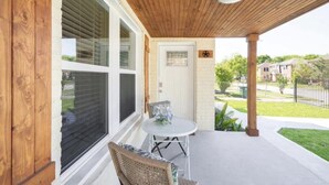 A covered patio with a table and chairs, a door with a window, and a view of a residential area. - Charming Home Near Midtown (Houston)