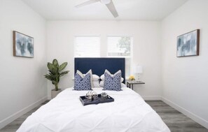 Relax in this serene bedroom with a large bed, ceiling fan, and two windows.