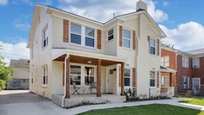 A two-story house with a covered porch, a garage, and a well-maintained lawn. - Charming Home Near Midtown (Houston)