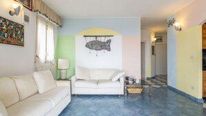 Ein Wohnzimmer mit einem weißen Sofa, einem Couchtisch und einer Wanddekoration in Form eines Fisches.
