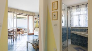 Ein Zimmer mit Essbereich, einer Glastür, die auf einen Balkon führt, und einer Küchenzeile mit Fliesenrückwand.