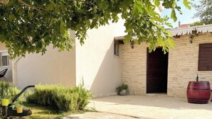 A courtyard with a stone wall, a wooden bench, and a red barrel. - Villa Meri by Interhome (Novigrad (Zadar))