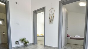 A spacious room with a light wood floor, a bicycle, a dreamcatcher, and a glimpse of a bathroom with a towel and a pink item. - Villa Meri by Interhome (Novigrad (Zadar))
