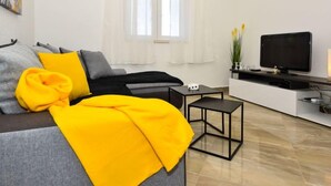 A modern living room with a grey sofa, yellow throw pillows, a black coffee table, and a flat-screen TV on a white entertainment unit. - Villa Meri by Interhome (Novigrad (Zadar))